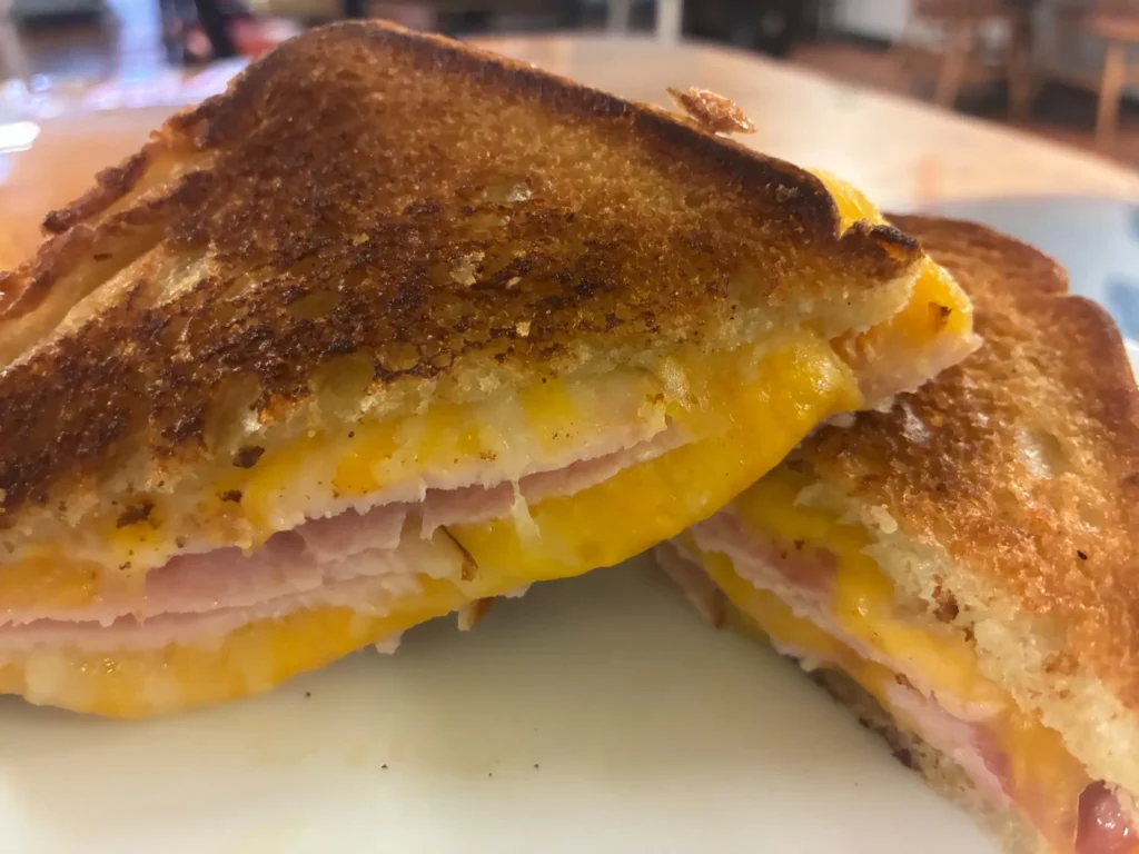 Close-up of a grilled ham and cheese sandwich cut in half, showing melted cheese and sliced ham between crisp toasted bread at Kat’s Café & Restaurant.