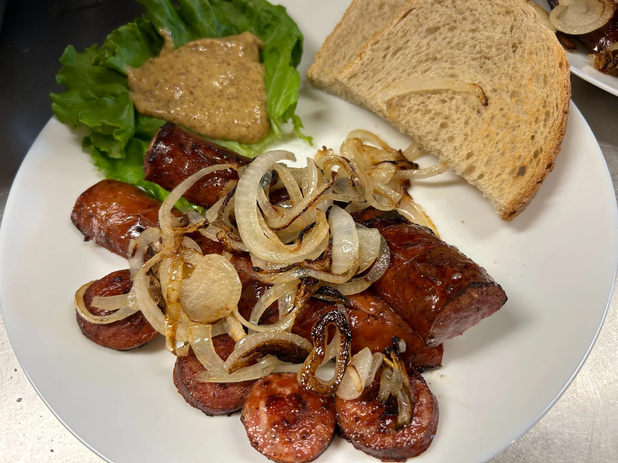 Pan-grilled kielbasa links and sliced kielbasa served with sautéed onions, lettuce, and mustard on a plate at Kat’s Café & Restaurant.