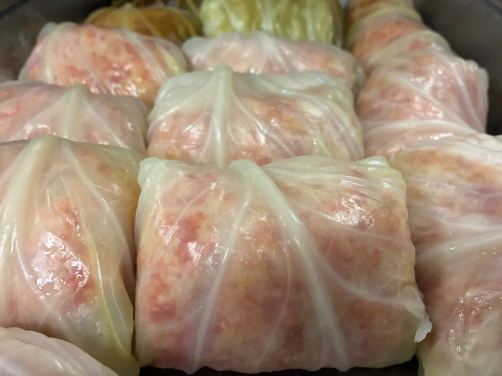 Hand-rolled stuffed cabbage rolls arranged closely in a pan before baking at Kat’s Café & Restaurant.