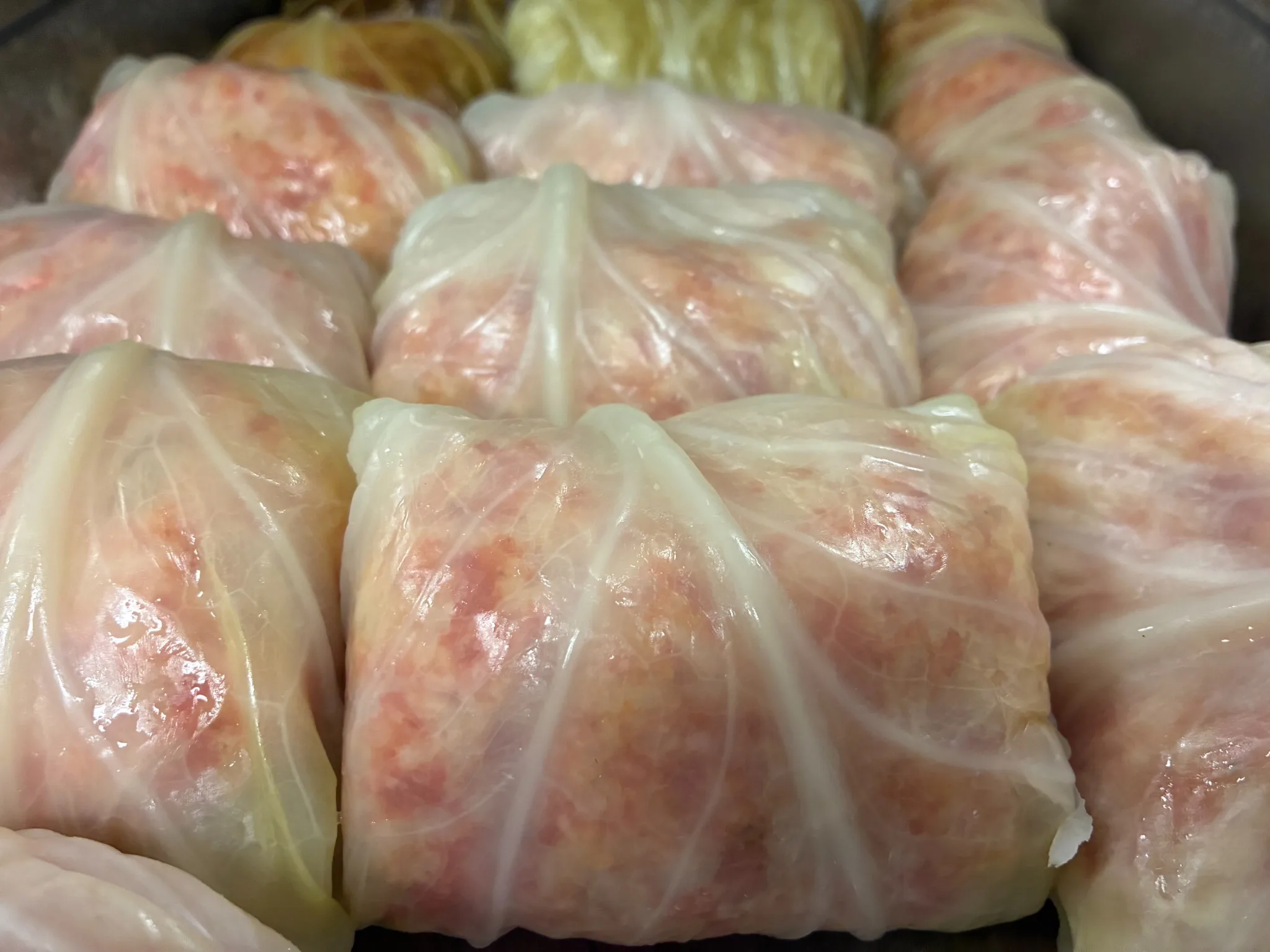 Hand-rolled stuffed cabbage rolls arranged closely in a pan before baking at Kat’s Café & Restaurant.