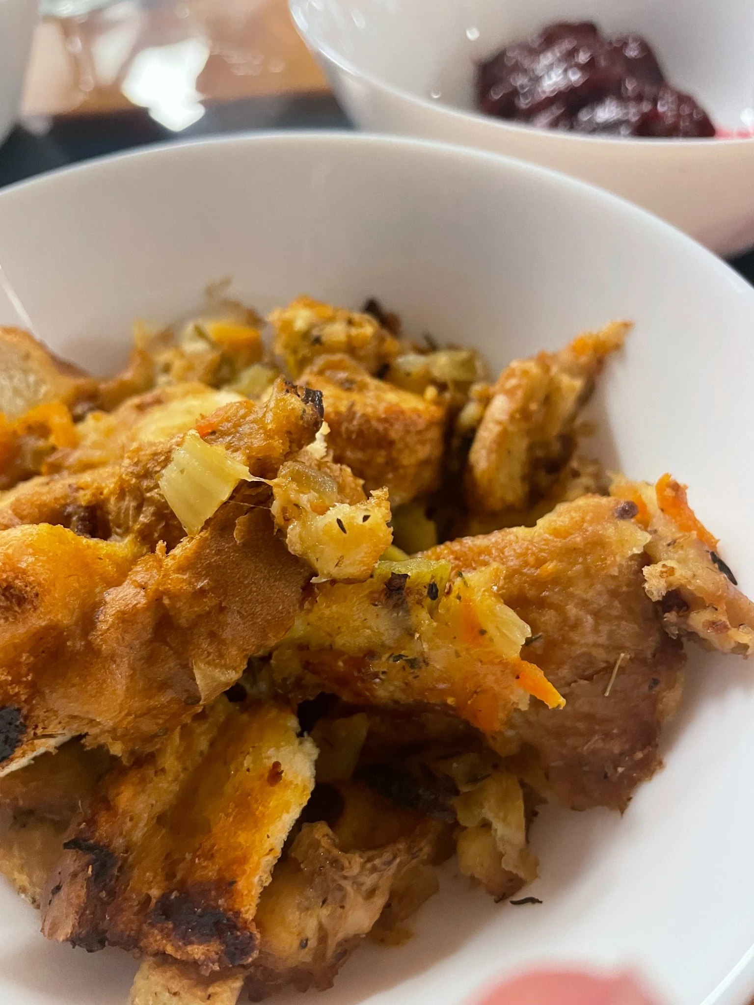 Close-up of homemade Thanksgiving stuffing at Kat’s Café & Restaurant with cranberry sauce in the background.