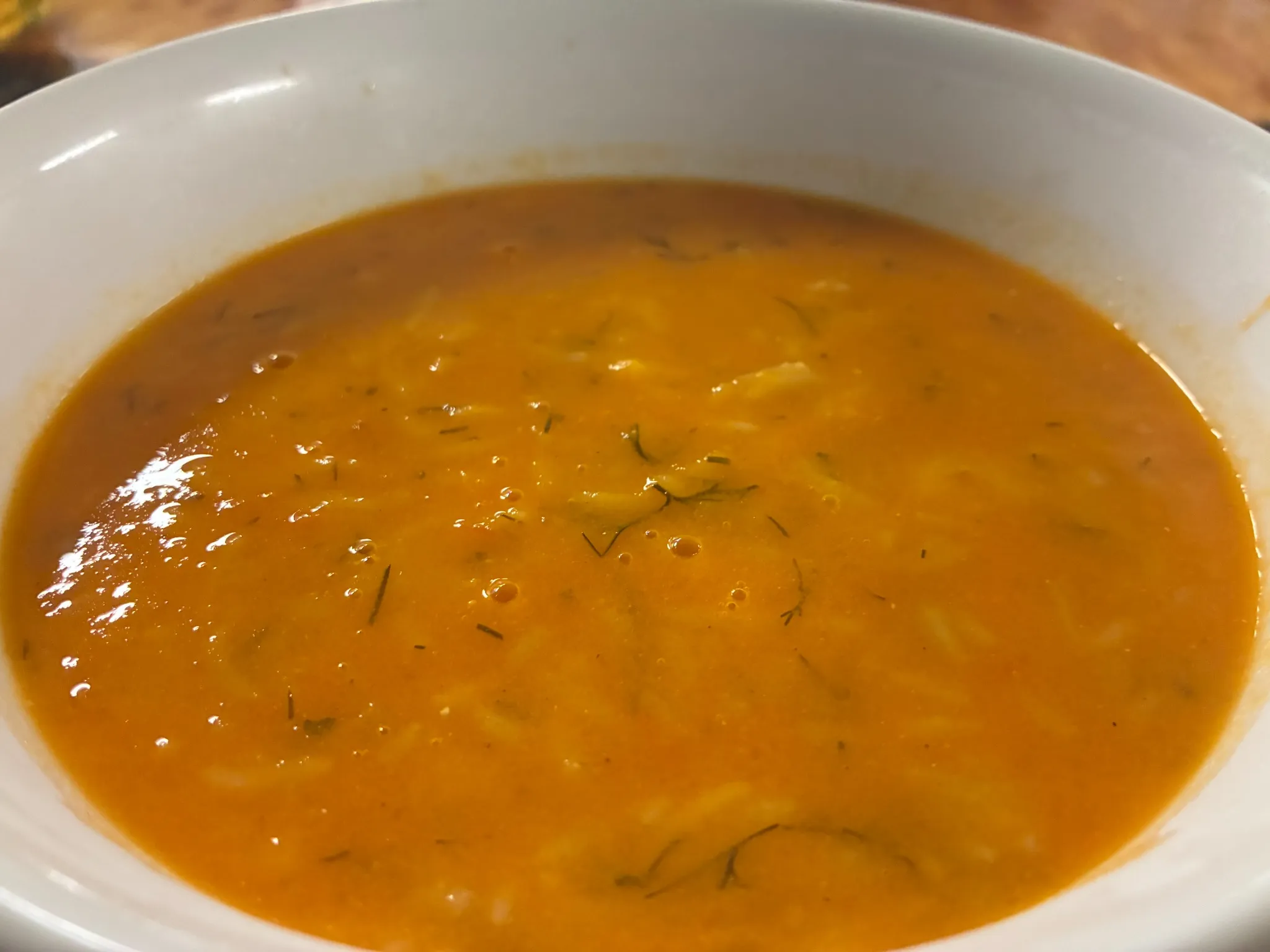 Creamy homemade tomato soup with fresh herbs in a white bowl at Kat’s Café & Restaurant.