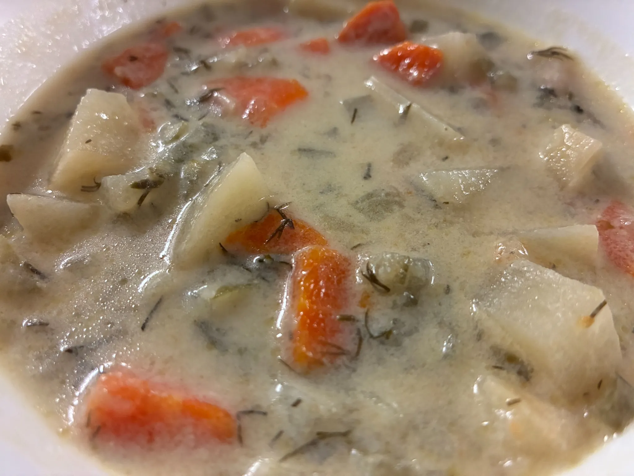 Creamy vegetable soup with potatoes, carrots, and herbs in a white bowl at Kat’s Café & Restaurant.