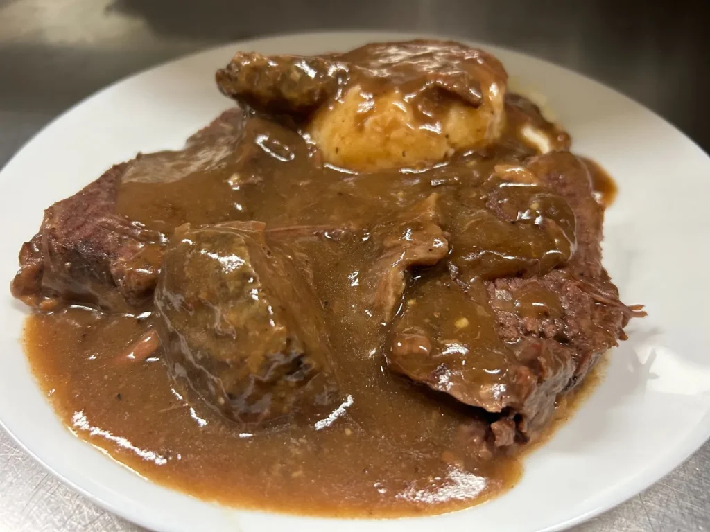 Sliced beef pot roast with real meat gravy, mashed potatoes, and a side of beets on a white plate at Kat’s Café & Restaurant.