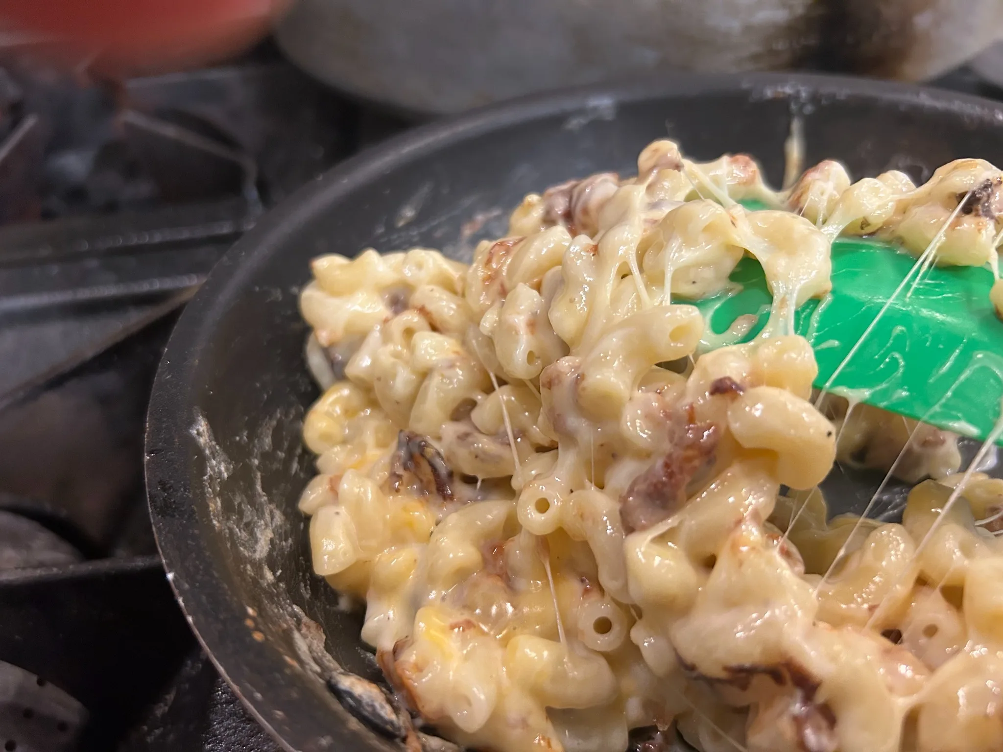 Creamy macaroni and cheese being stirred in a skillet in the kitchen at Kat’s Café & Restaurant.