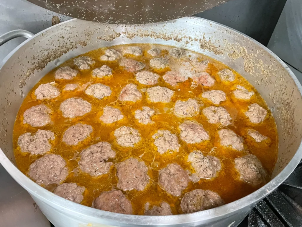 House-made meatballs simmering in sauce in a large pan at Kat’s Café & Restaurant.