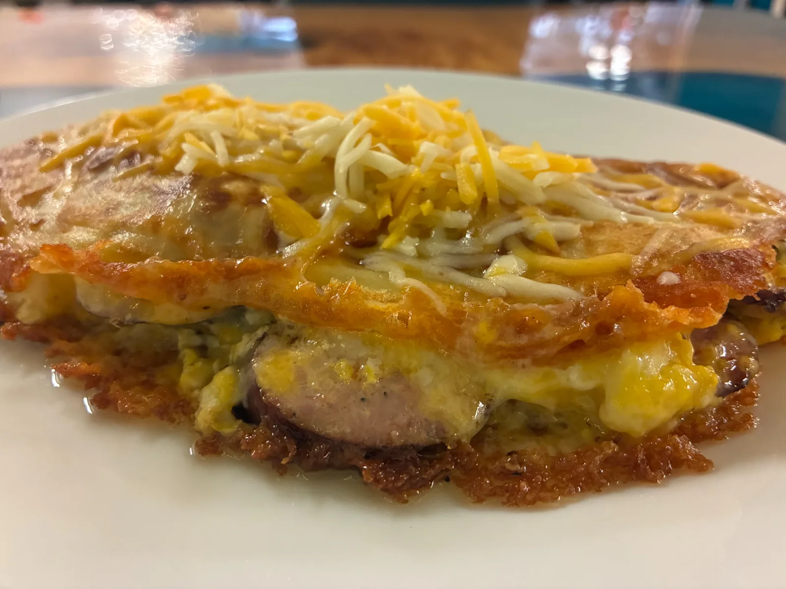 Close-up of a kielbasa, egg, and cheese crepe with sliced kielbasa, scrambled eggs, and shredded cheese served on a white plate at Kat’s Café & Restaurant.