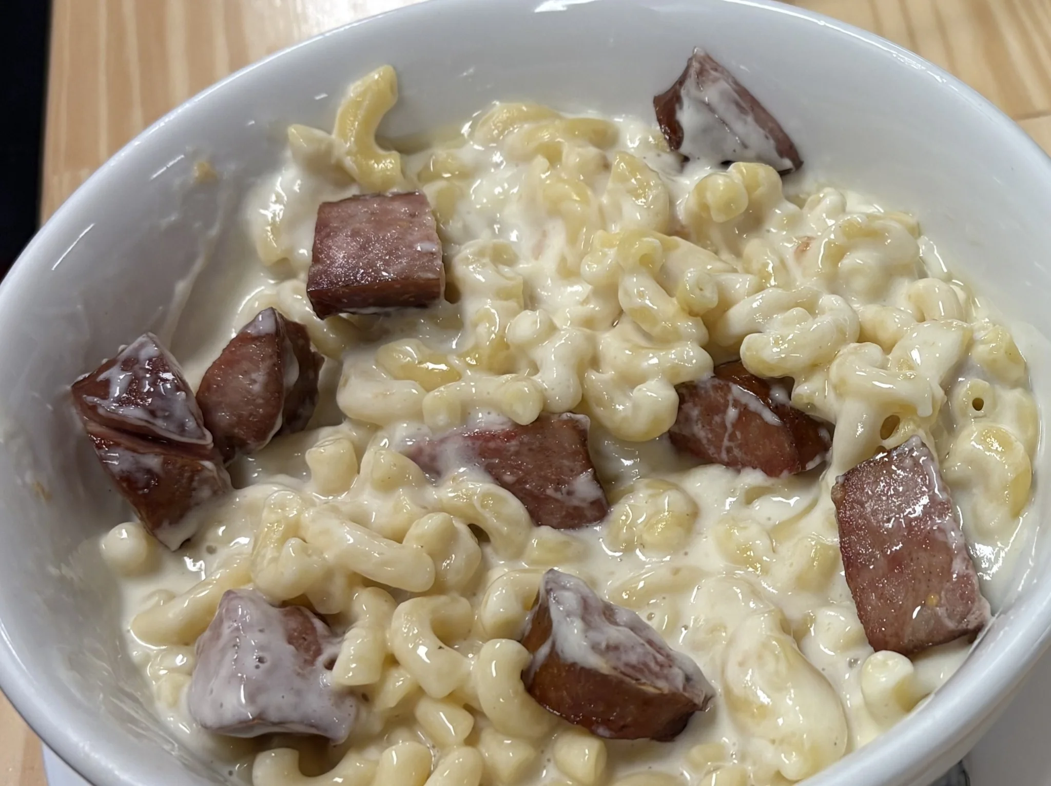 Bowl of homemade creamy macaroni and cheese with sliced kielbasa.