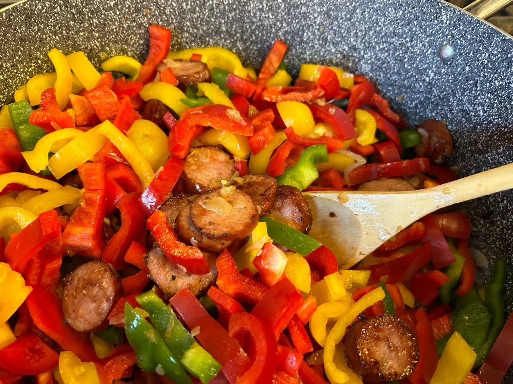 Sliced kielbasa and red, yellow, and green peppers cooking together for letcho in the kitchen at Kat’s Café & Restaurant.