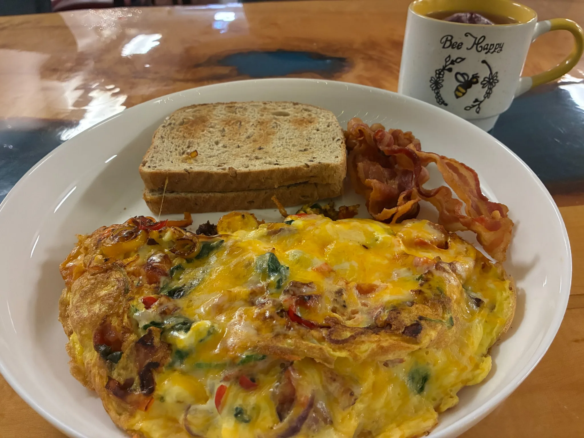 Loaded vegetable-and-cheese omelet served with toast, bacon, and a mug of tea, at Kat’s Café & Restaurant.
