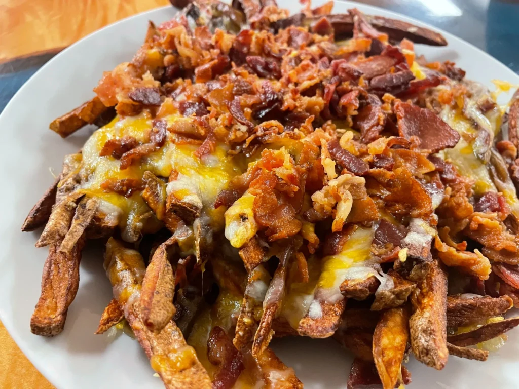 Plate of loaded fries topped with melted cheddar cheese and chopped bacon at Kat’s Café & Restaurant.