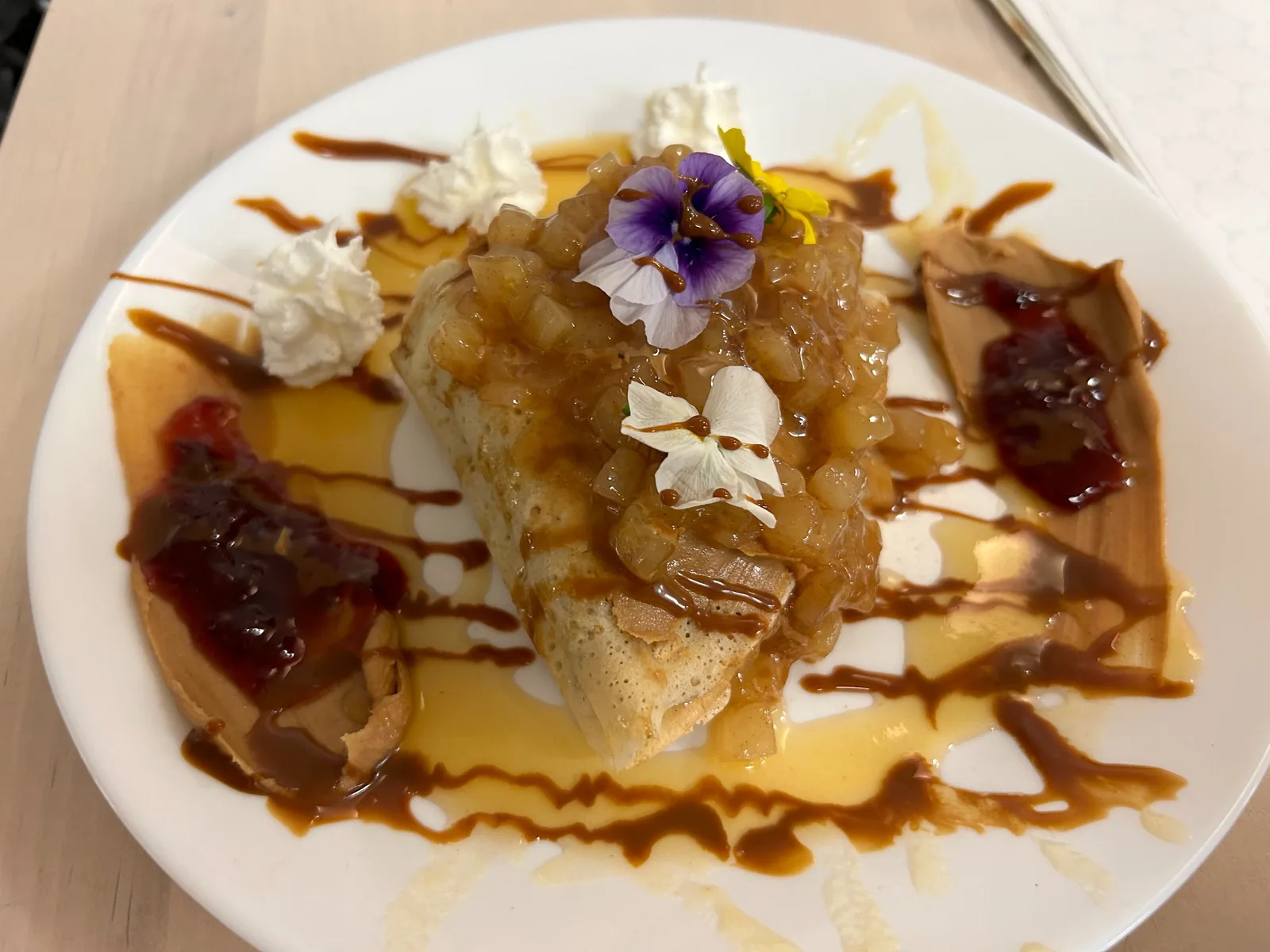 PB&J crepe plated with peanut butter, fruit preserves and topping, whipped cream, caramel drizzle, and edible flowers at Kat’s Café & Restaurant.