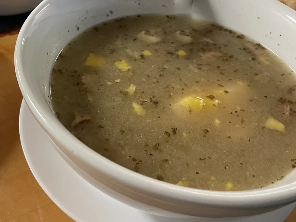 Traditional Polish żurek soup with egg, white kielbasa, and herbs in a white bowl at Kat’s Café & Restaurant.