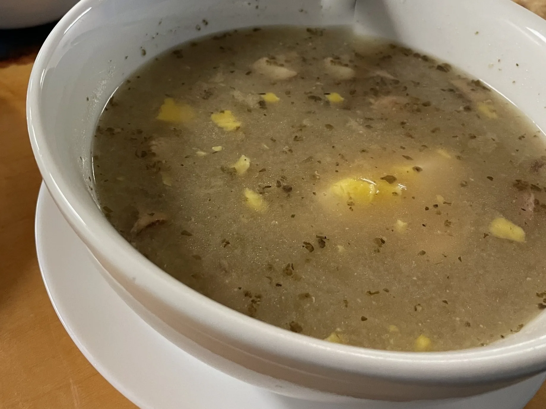 Traditional Polish żurek soup with egg, white kielbasa, and herbs in a white bowl at Kat’s Café & Restaurant.