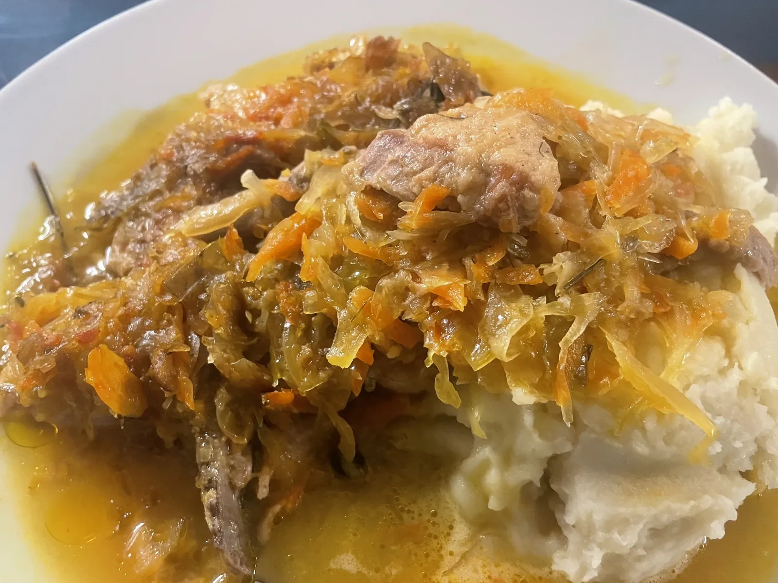 Slow-cooked pork and homemade sauerkraut served over mashed potatoes on a white plate at Kat’s Café & Restaurant.