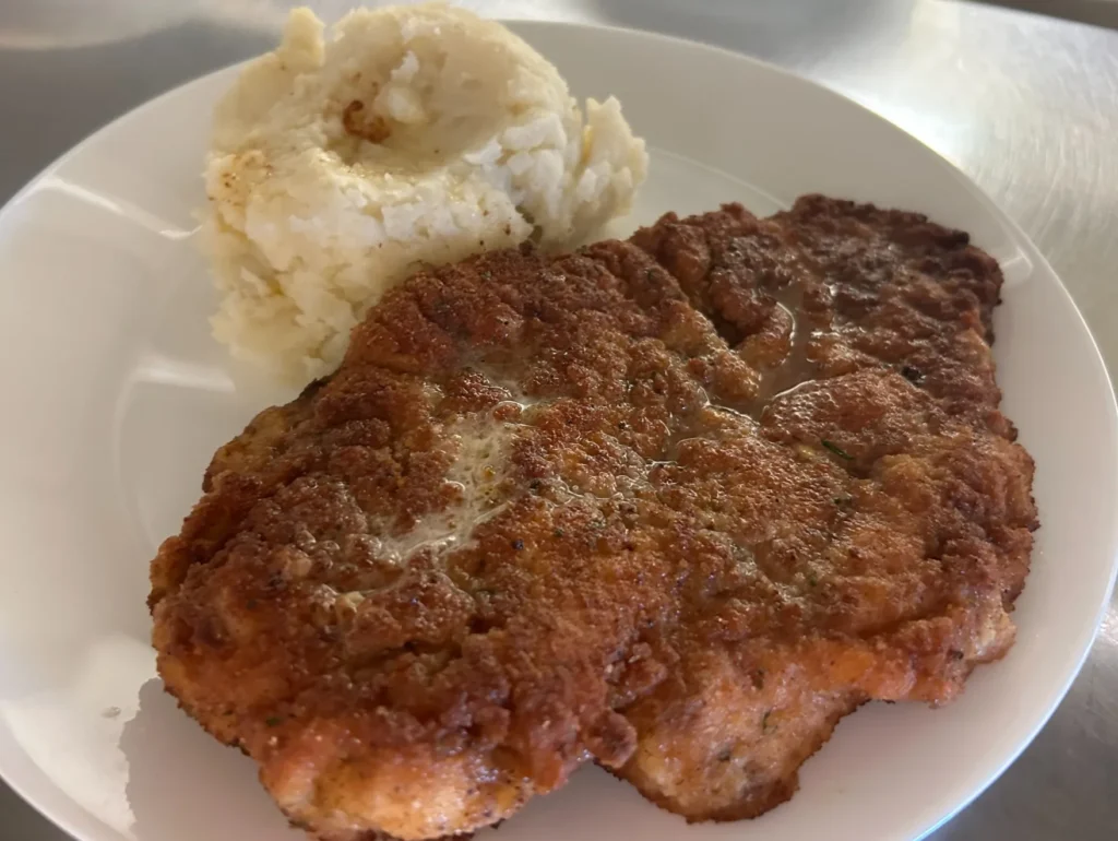 Breaded pork schnitzel cutlet served on a plate with a scoop of mashed potatoes at Kat’s Café & Restaurant.