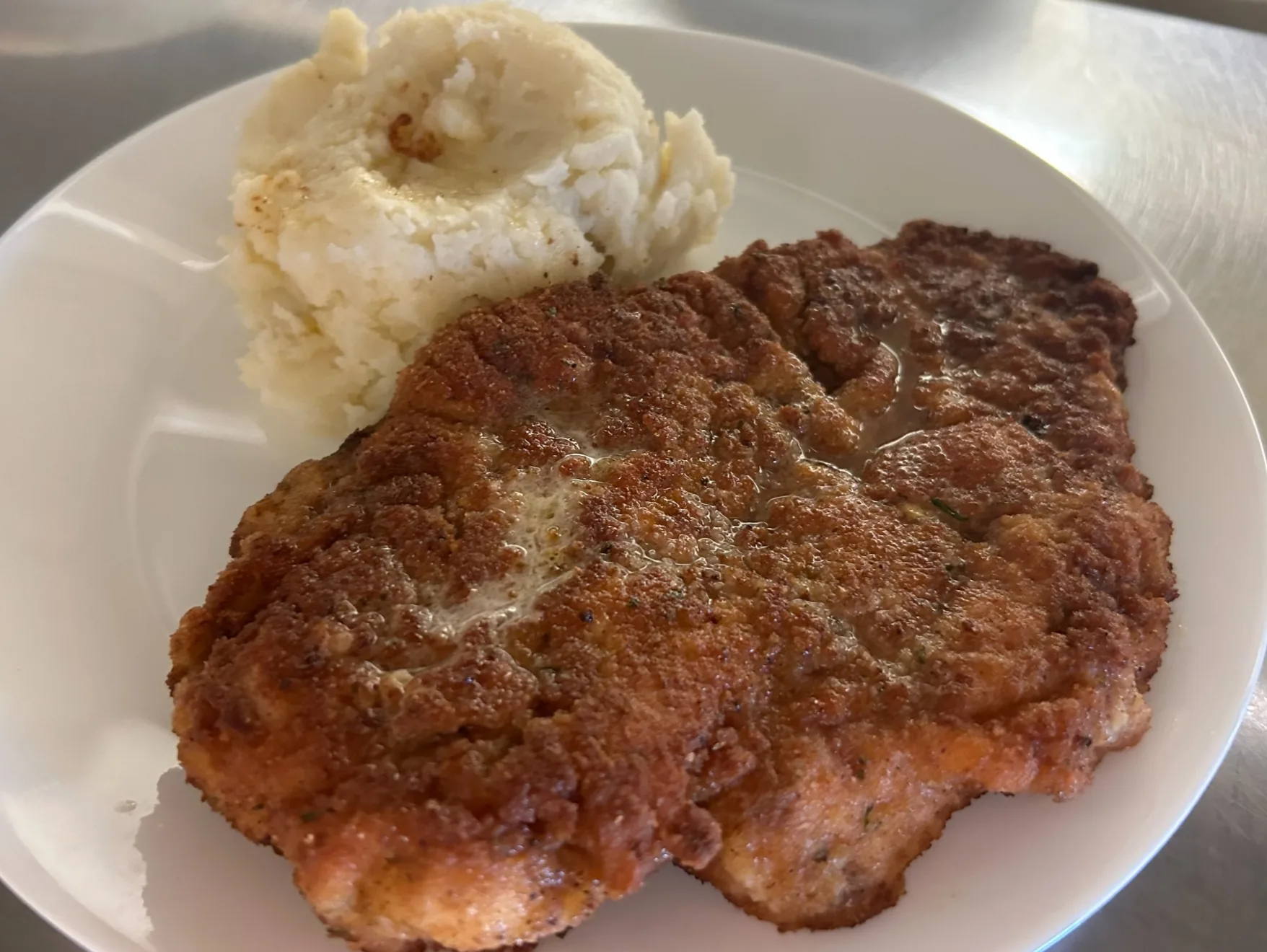 Breaded pork schnitzel cutlet served on a plate with a scoop of mashed potatoes at Kat’s Café & Restaurant.