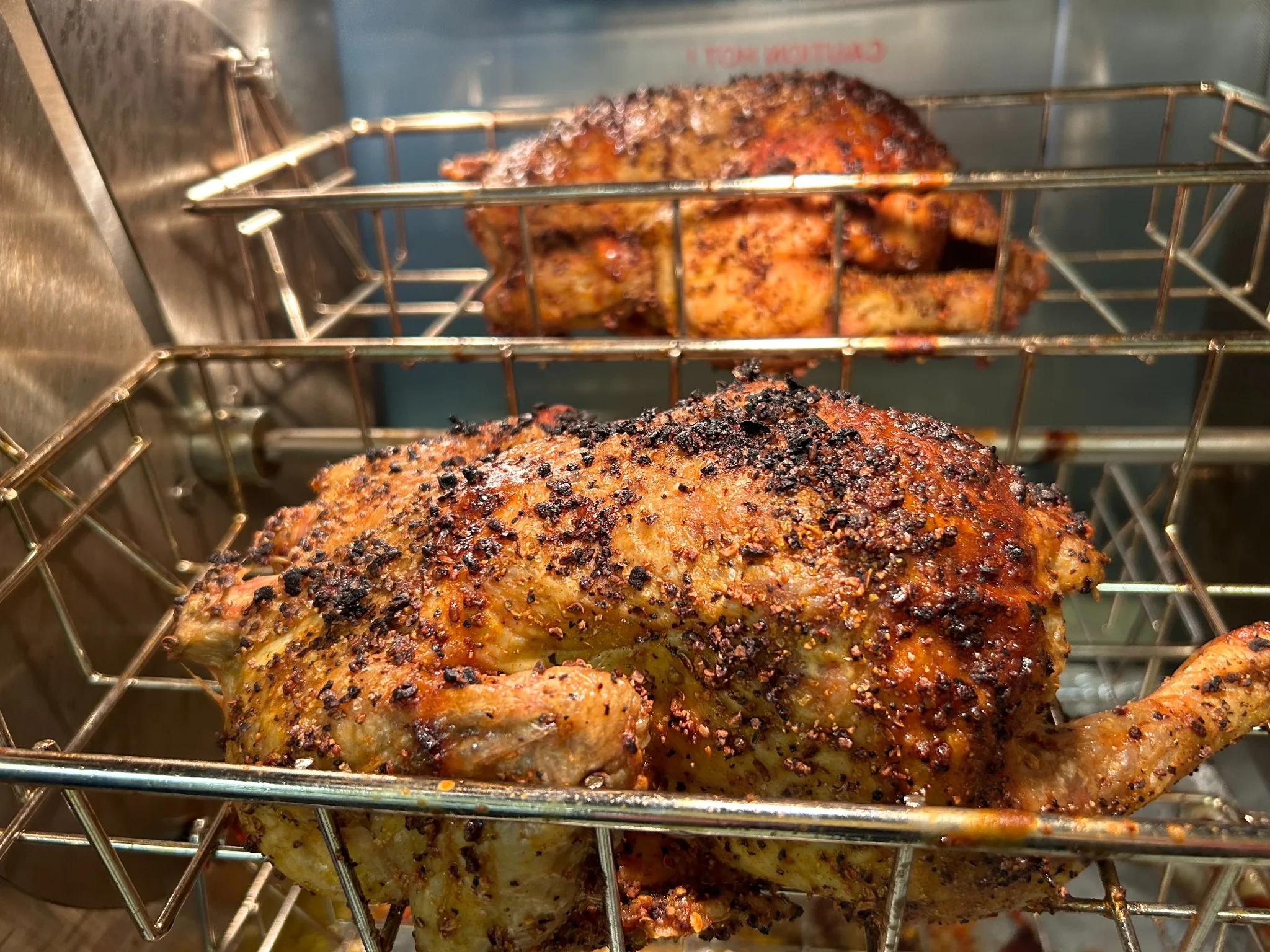 Whole seasoned chickens roasting in a rotisserie oven at Kat’s Café & Restaurant.