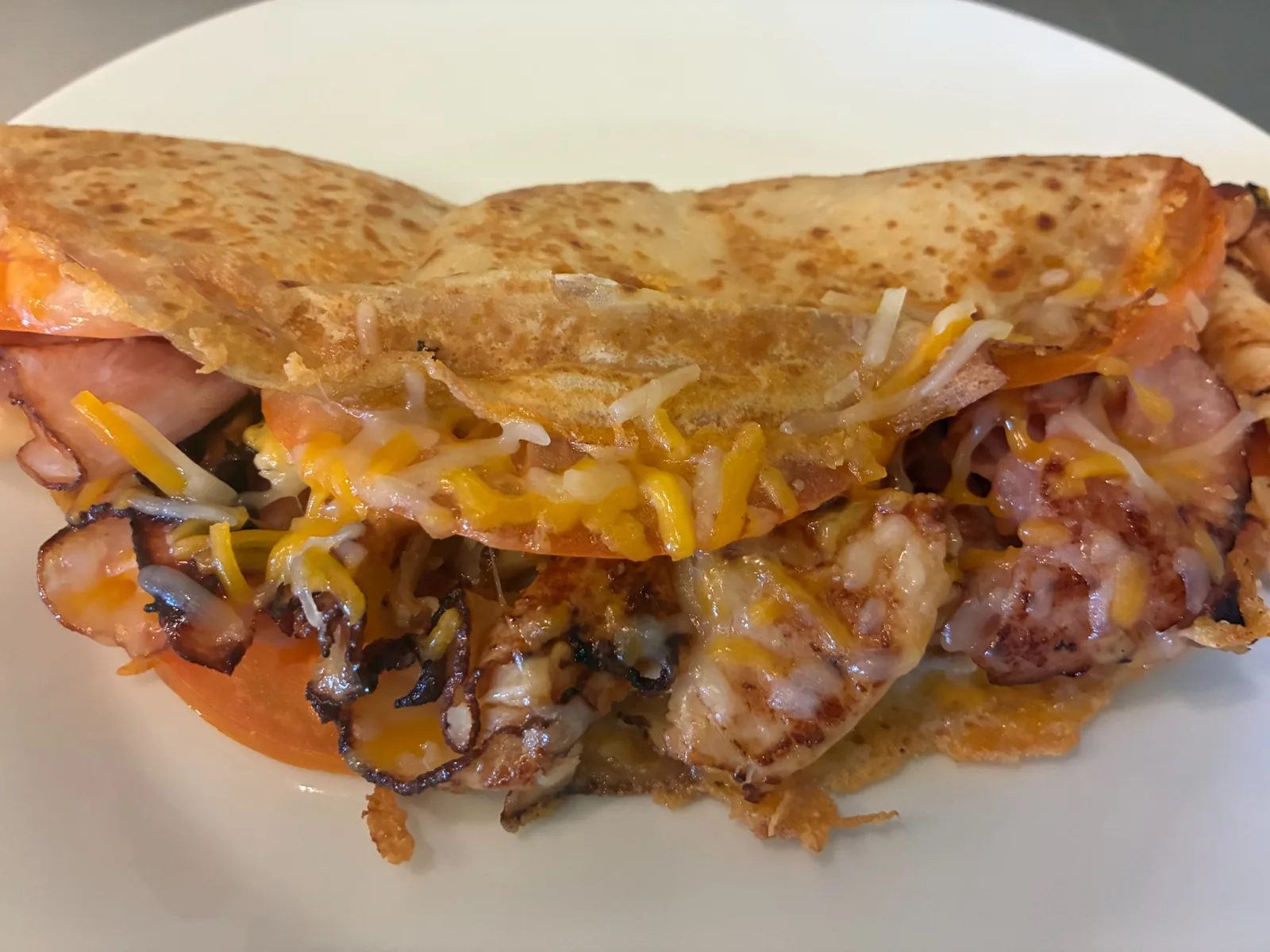 Panini-style savory crepe filled with ham, tomato, and melted cheese on a white plate at Kat’s Café & Restaurant.