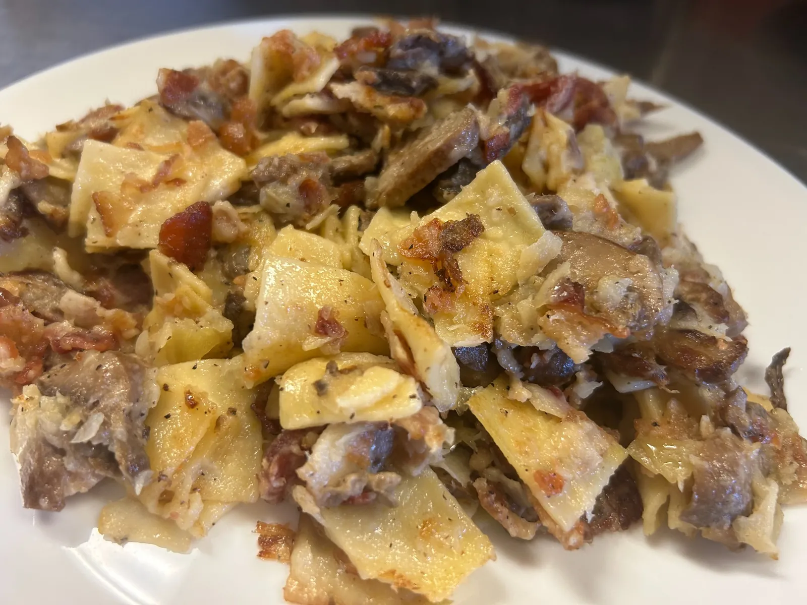 Haluski with wide noodles, cabbage, mushrooms, and bacon served on a white plate at Kat’s Café & Restaurant.