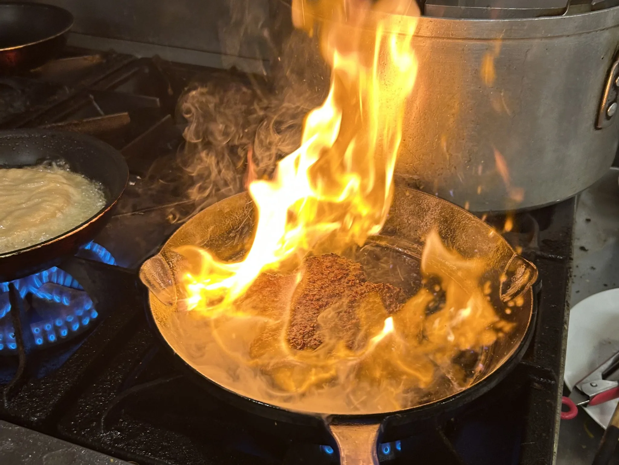 A smash burger patty being flame-seared in a cast-iron skillet at Kat’s Café & Restaurant.