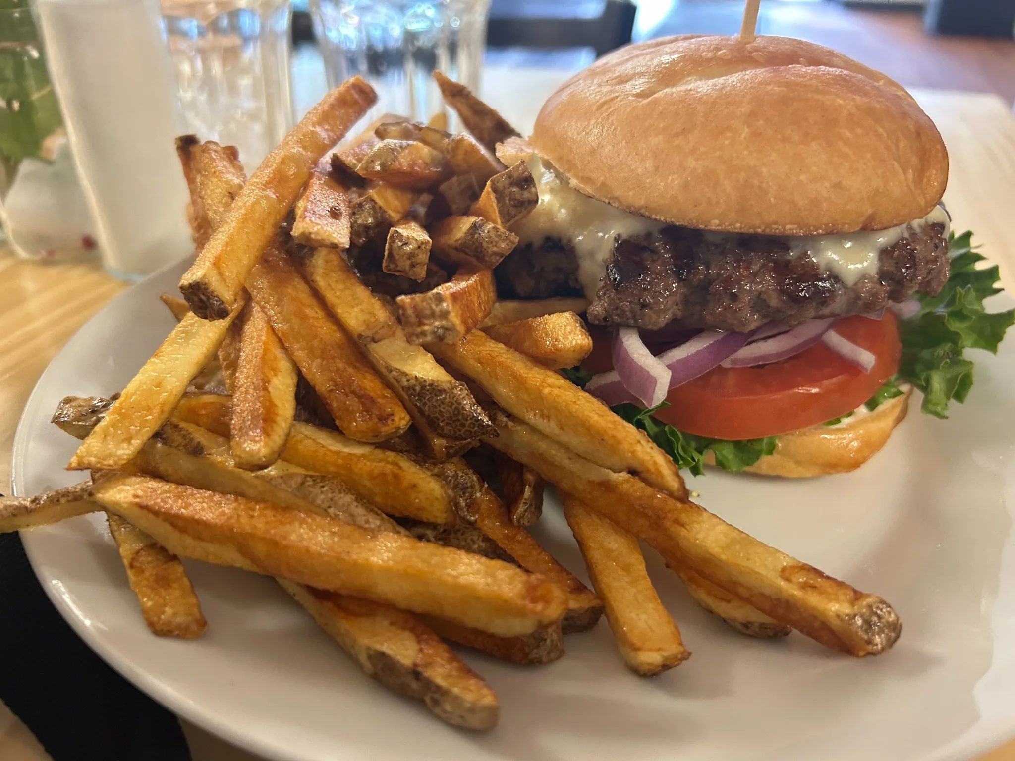 Smash burger with melted cheese, lettuce, tomato, and red onion, served with a generous portion of skin-on fries at Kat’s Café & Restaurant.