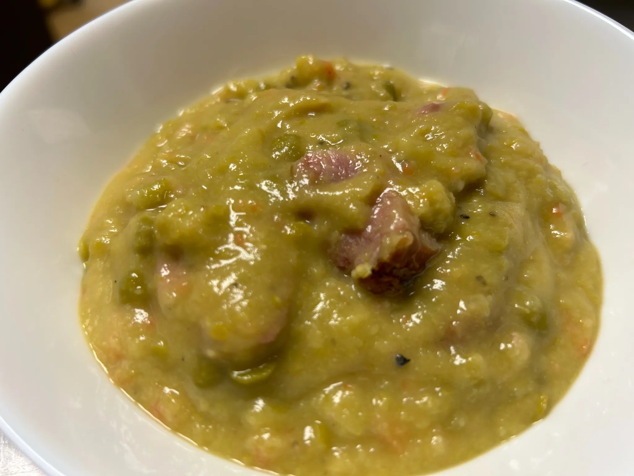 Thick split pea soup with pieces of smoky ham in a white bowl at Kat’s Café & Restaurant.