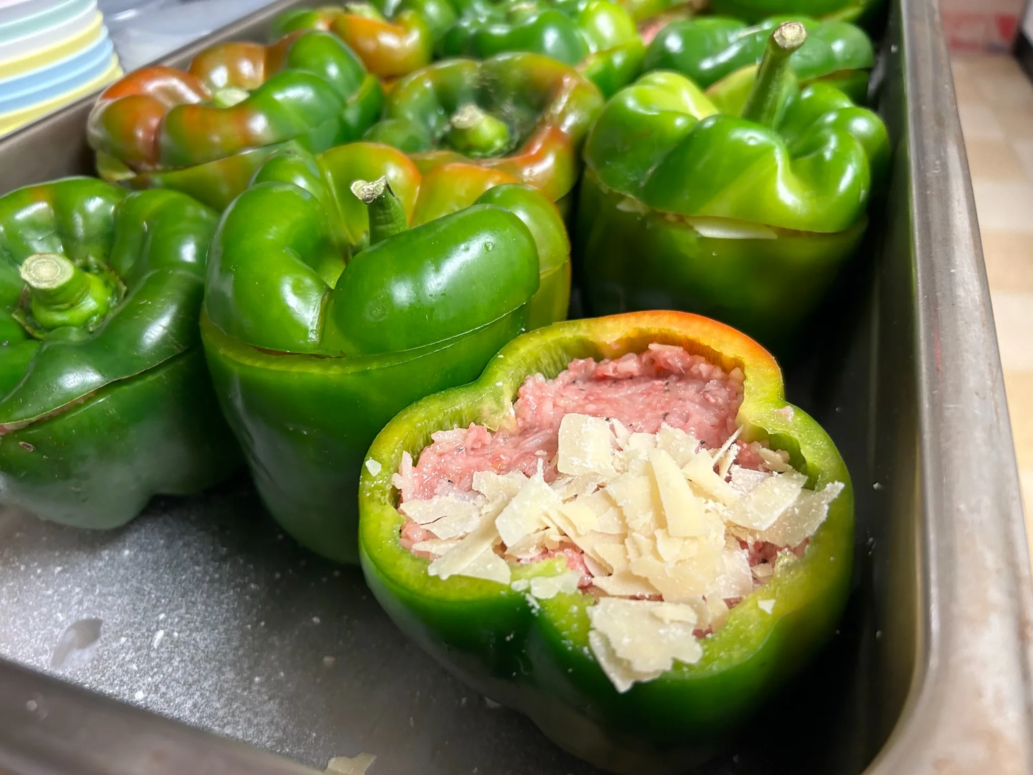 Green bell peppers filled with seasoned meat and topped with shaved cheese before baking in the kitchen at Kat’s Café & Restaurant.