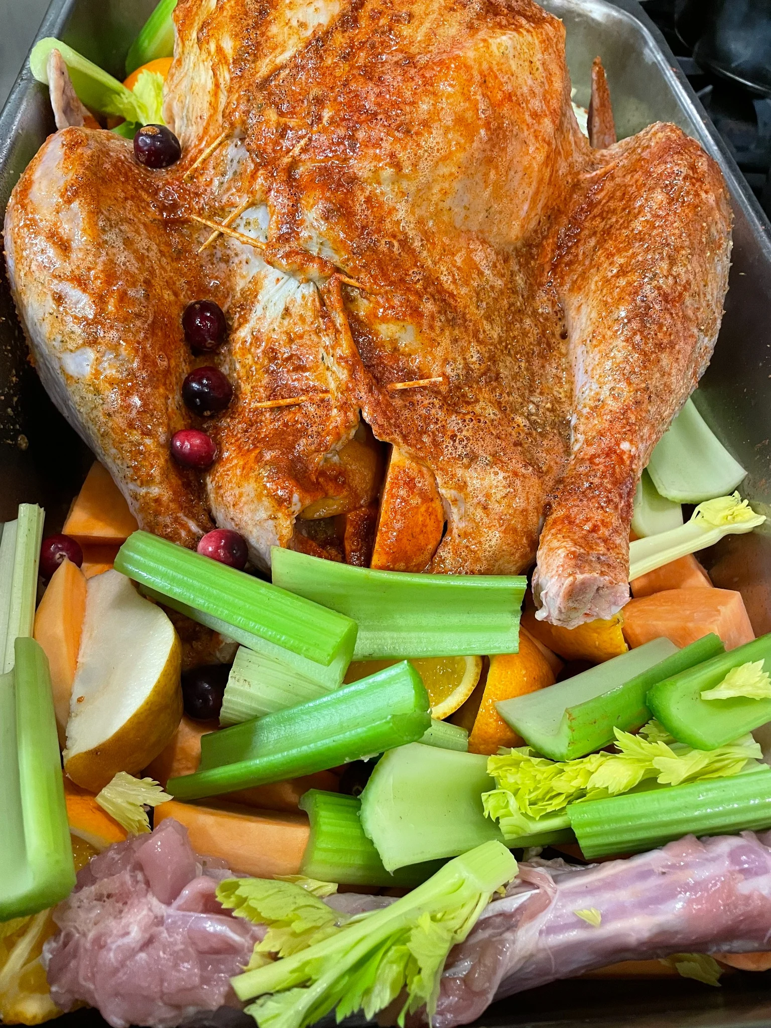 Seasoned Thanksgiving turkey in a roasting pan with celery, sweet potatoes, pears, oranges, and cranberries at Kat’s Café & Restaurant.