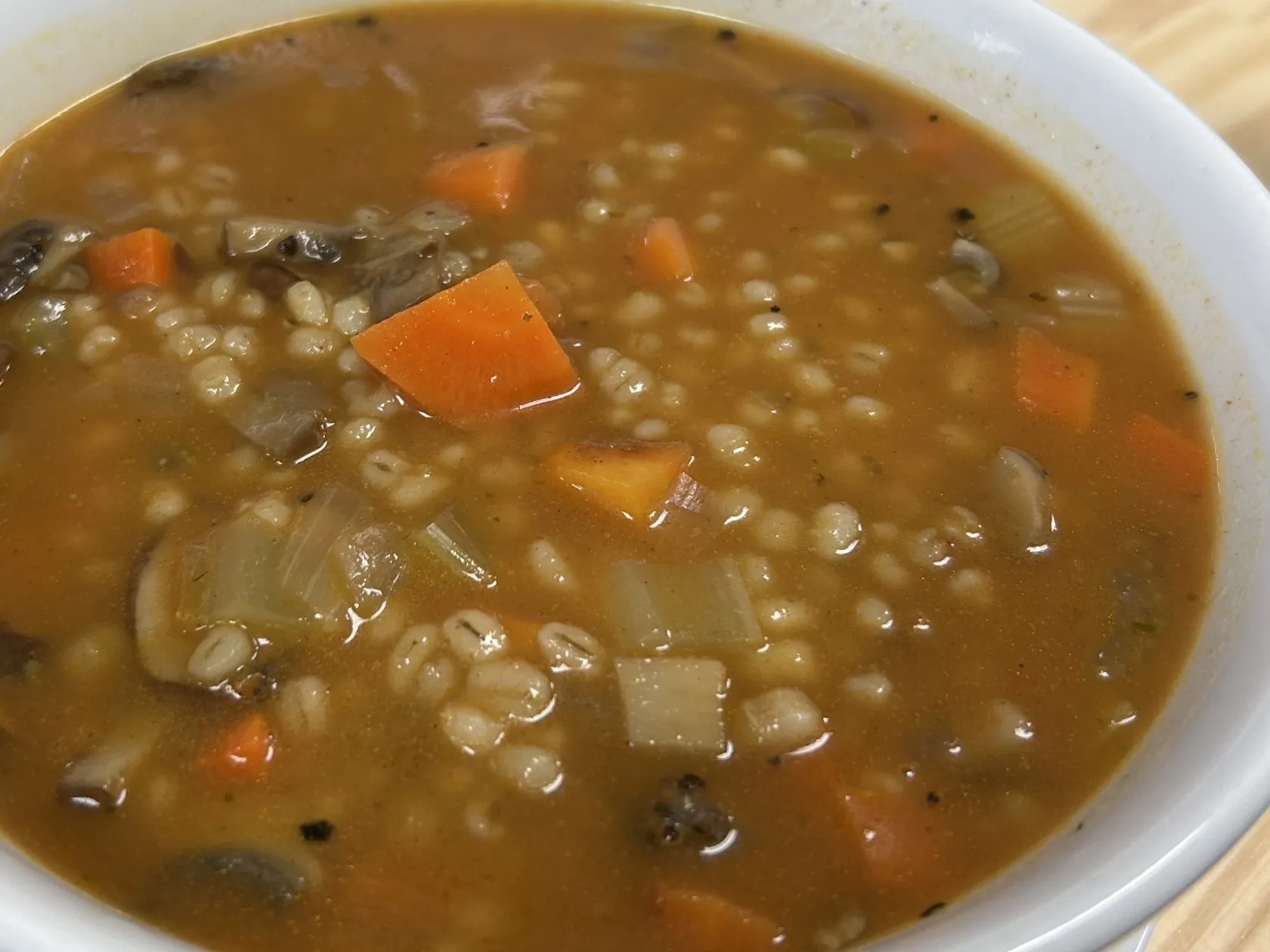 Vegan mushroom barley soup with mushrooms, barley, carrots, celery, and onions in a white bowl at Kat’s Café & Restaurant.