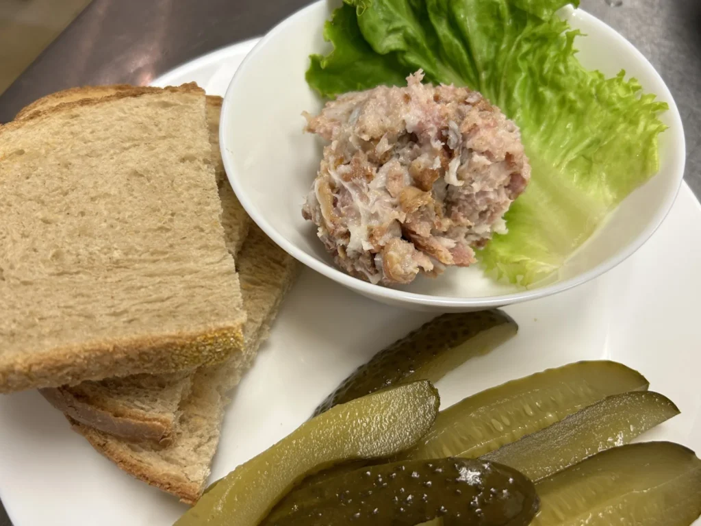 Rustic house spread served in a bowl with lettuce, sliced bread, and pickle spears on a plate at Kat’s Café & Restaurant.