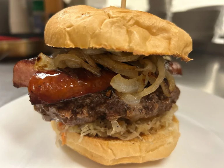 Beef burger topped with grilled kielbasa, sautéed onions, and sauerkraut on a fresh bun at Kat’s Café & Restaurant.