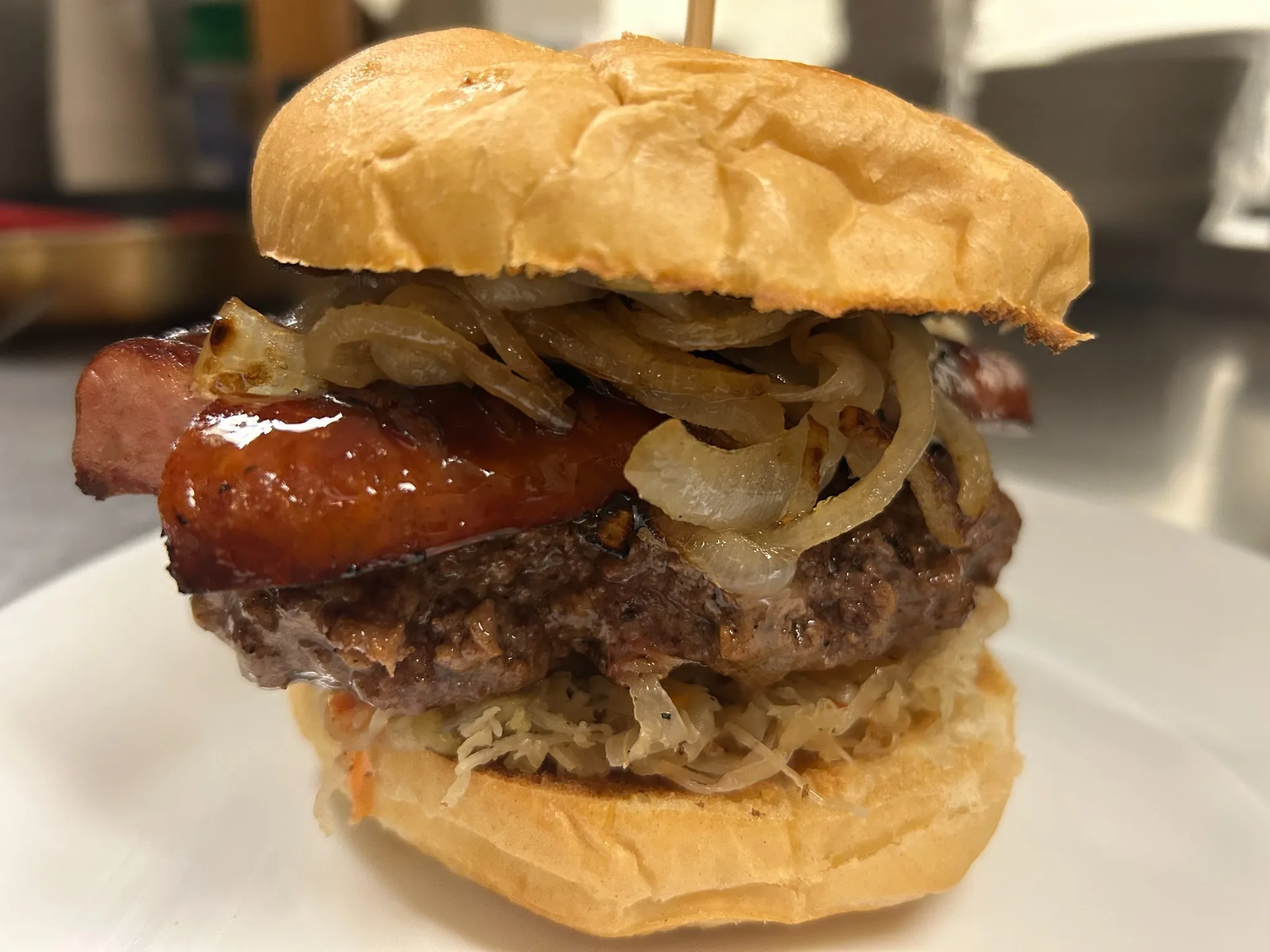 Beef burger topped with grilled kielbasa, sautéed onions, and sauerkraut on a fresh bun at Kat’s Café & Restaurant.