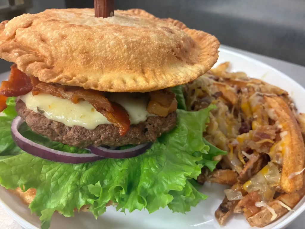 Pierogi burger with a beef patty, melted cheese, bacon, lettuce, and red onion, served with loaded fries at Kat’s Café & Restaurant.