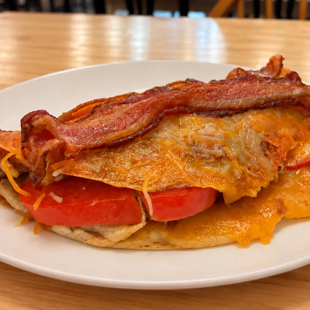 Pan-grilled savory crepe at Kat’s Café & Restaurant filled with crispy bacon, fresh tomatoes, sautéed onions, and melted cheese.