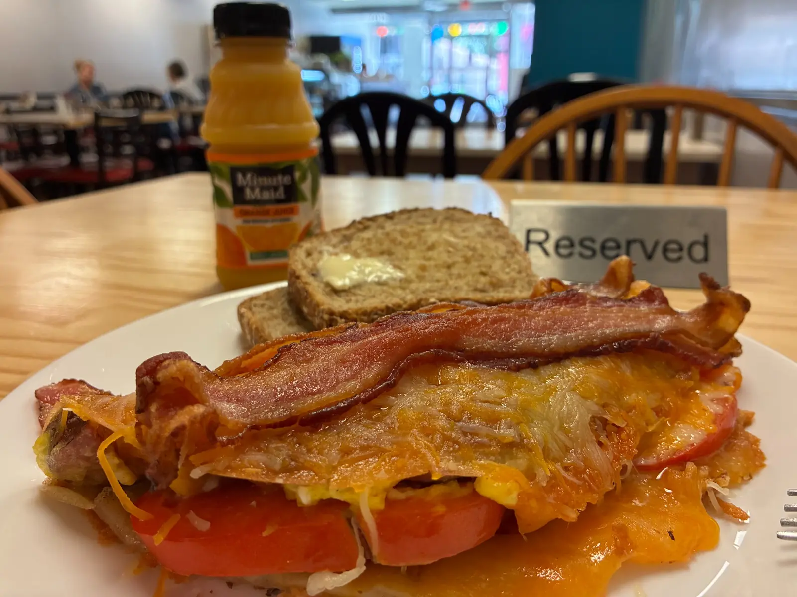 Bacon, tomato, and cheese savory crepe at Kat’s Café & Restaurant, served with orange juice and buttered rye toast against a softly blurred restaurant interior.