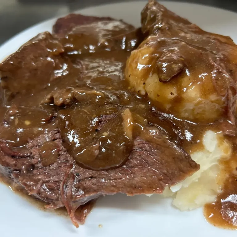 Tender slices of beef pot roast at Kat’s Café & Restaurant with mashed potatoes, covered in rich brown gravy on a white plate.