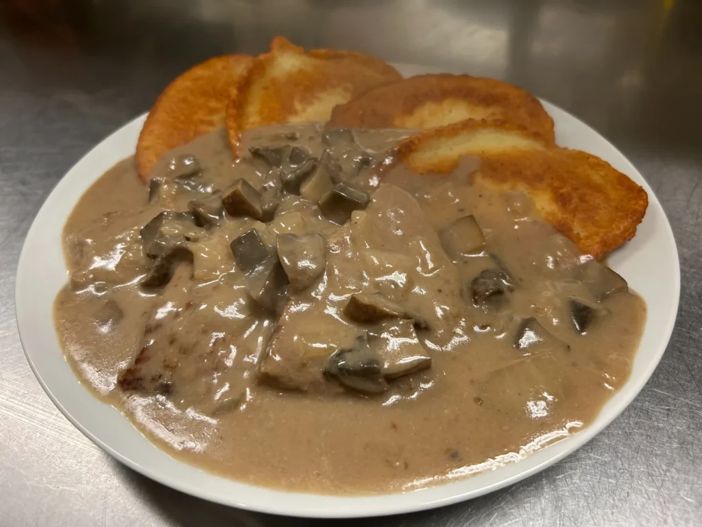Beef stroganoff with sliced mushrooms in creamy sauce, served with golden potato bleenies at Kat’s Café & Restaurant.