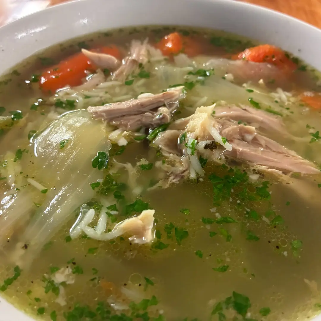 Homemade chicken soup at Kat’s Café & Restaurant, with shredded chicken, carrots, vegetables and herbs in a white bowl.