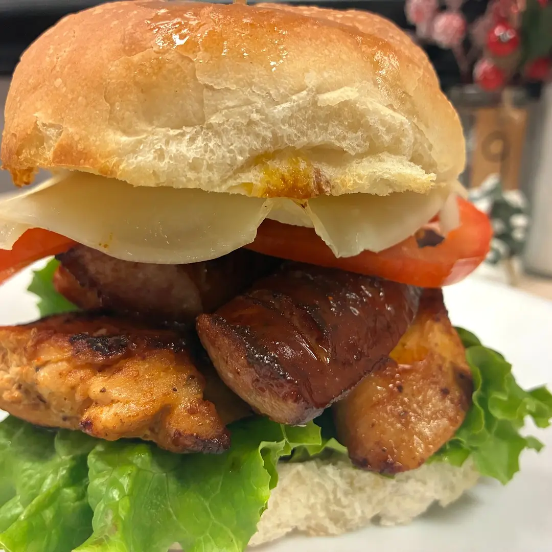 Grilled chicken and Polish kielbasa sandwich at Kat’s Café & Restaurant with cheese, lettuce, and tomato on a fresh roll.