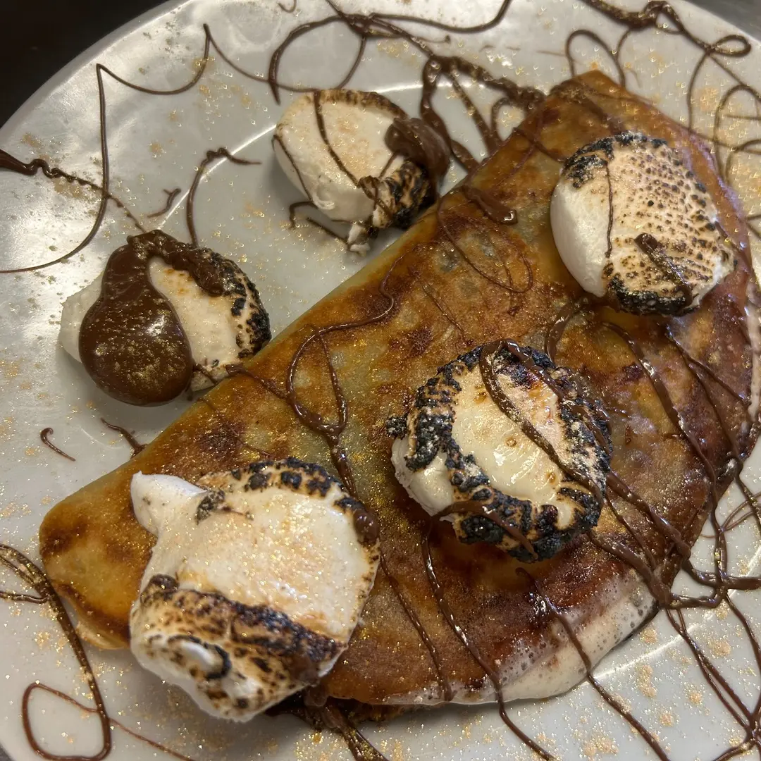 Nutella S’mores Crepe at Kat’s Café & Restaurant topped with fire-toasted marshmallows, chocolate drizzle, and powdered sugar.