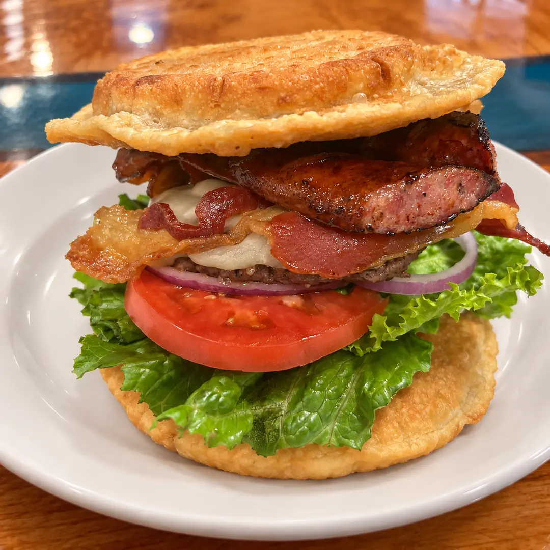 Pierogi Kielbasa Smash Burger with beef, smoked Polish kielbasa, bacon, melted cheese, lettuce, tomato, and red onion between two extra-large fried potato-and-cheese pierogies at Kat’s Café & Restaurant.