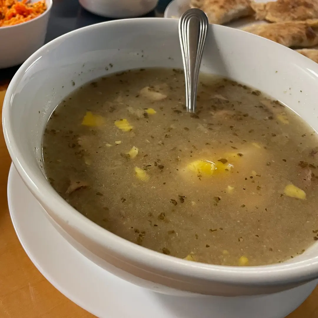 Traditional Polish żurek sour rye soup at Kat’s Café & Restaurant, with hardboiled egg, kielbasa, and herbs in a white bowl.