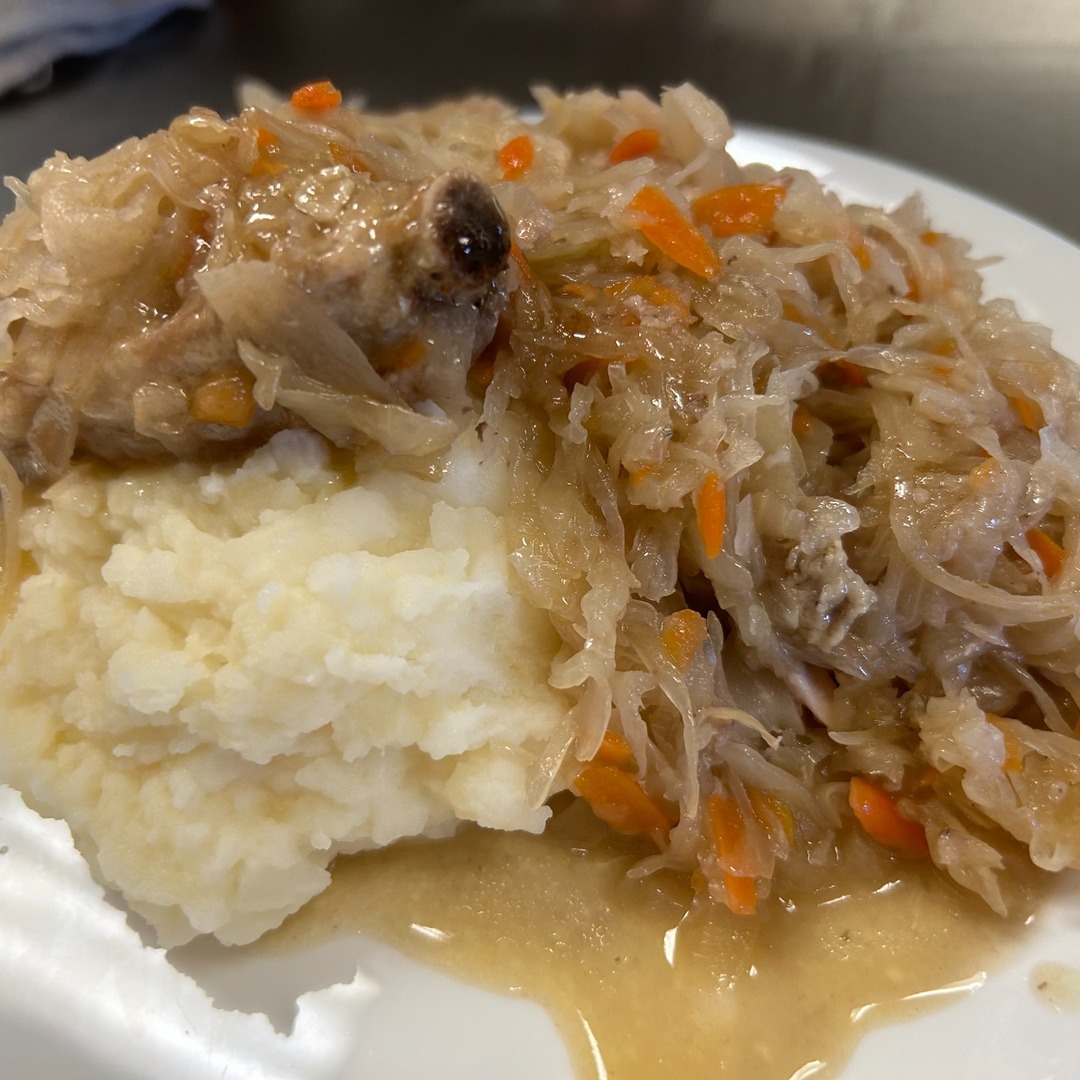Tender pork and sauerkraut with carrots dinner at Kat’s Café & Restaurant, served alongside mashed potatoes on a white plate.