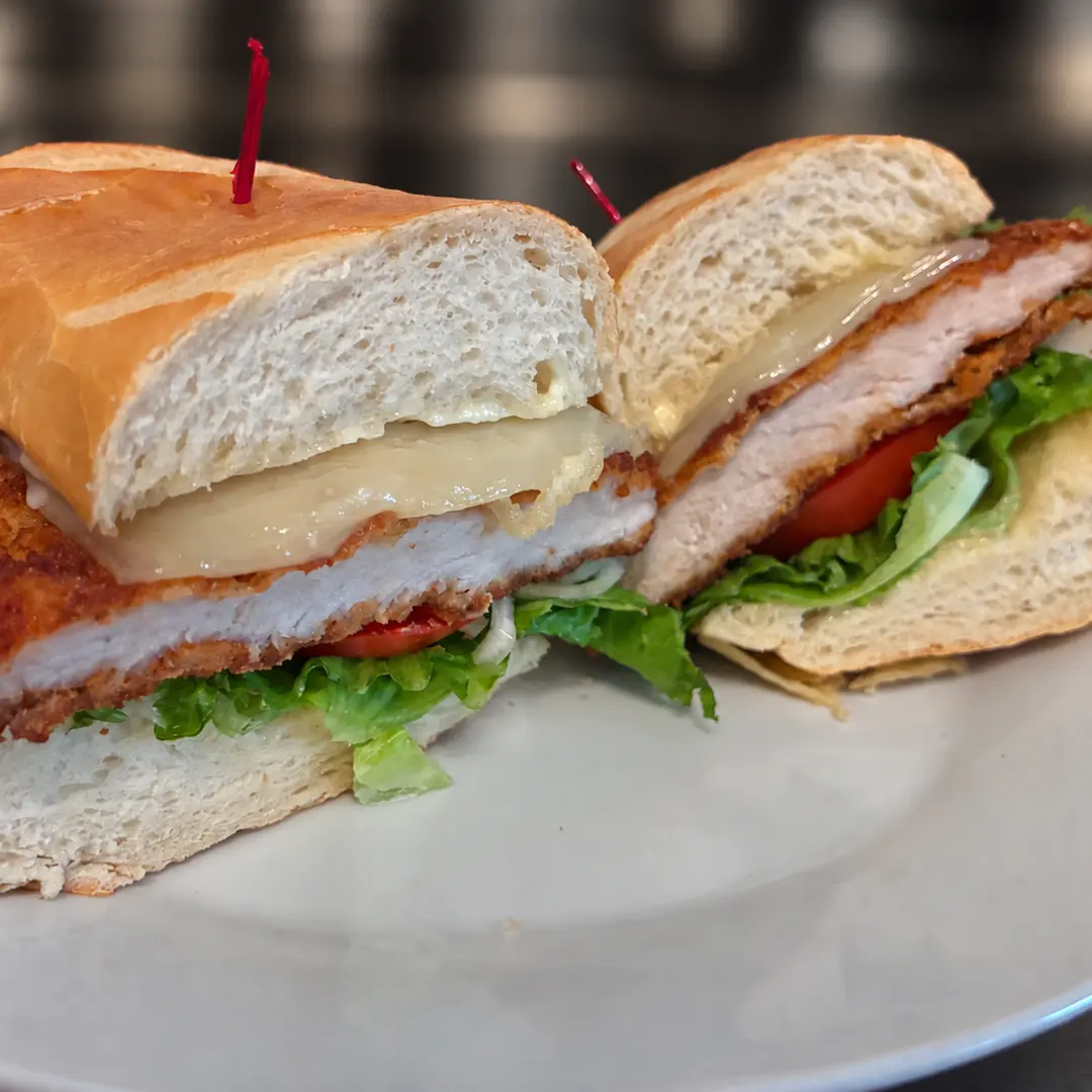 Pork Schnitzel Sub Kat’s Café & Restaurant features a freshly seasoned, golden-breaded pork cutlet topped with crisp lettuce, ripe tomato, red onion, and mayonnaise on a fresh hoagie roll.