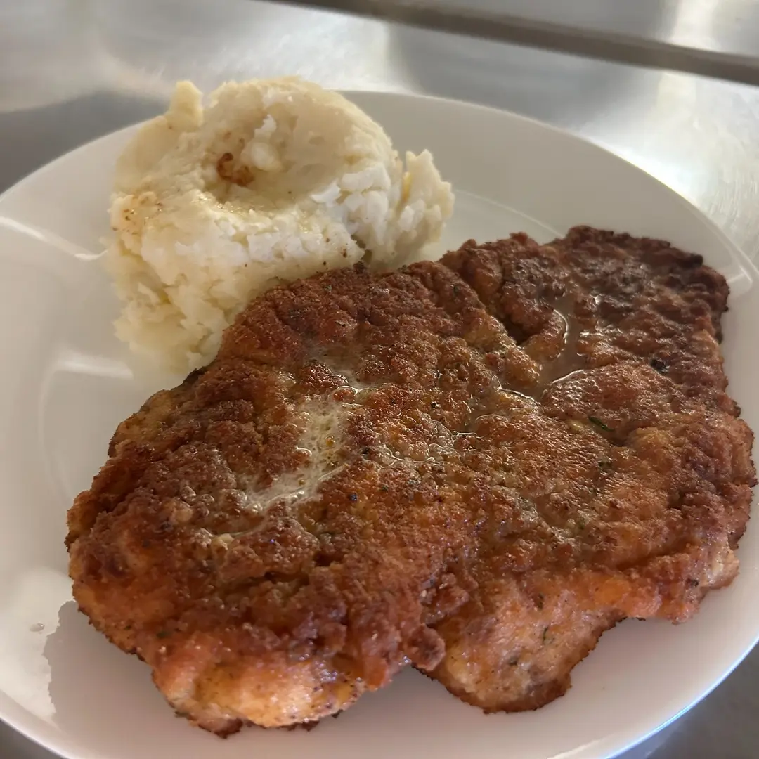 Large, golden-brown breaded pork schnitzel at Kat’s Café & Restaurant, served with a generous portion of mashed potatoes.