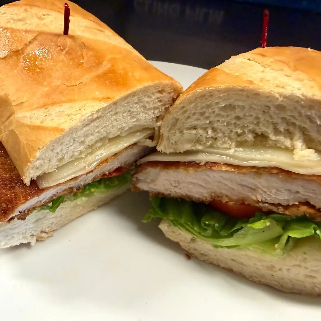Pork Schnitzel Sub at Kat’s Café & Restaurant features a freshly seasoned, golden-breaded pork cutlet topped with crisp lettuce, ripe tomato, red onion, and mayonnaise on a fresh hoagie roll.
