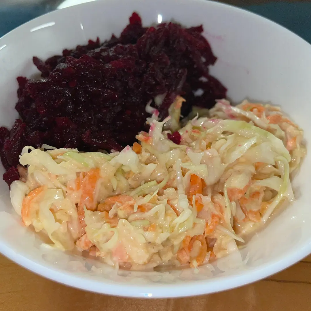 Kat’s house-made Slavic veggie salads featuring shredded beets and creamy cabbage-and-carrot slaw in a white bowl.
