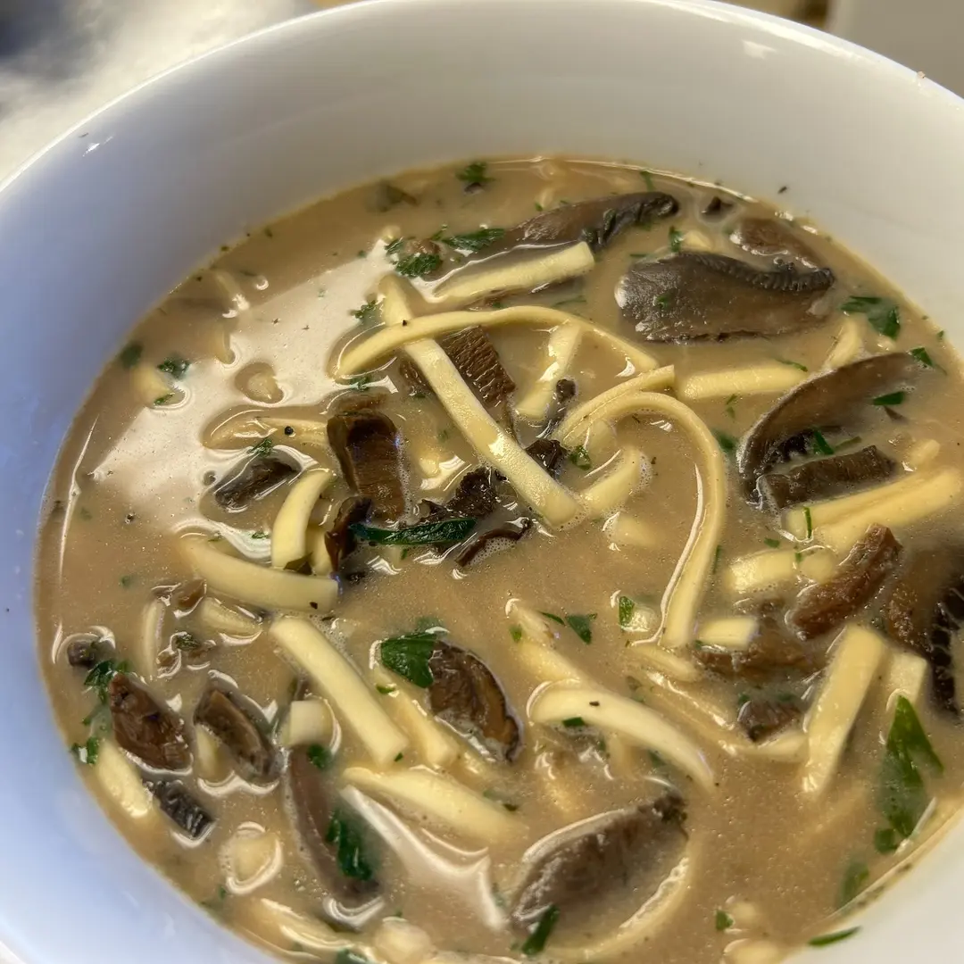 Homemade vegetarian wild mushroom soup at Kat’s Café & Restaurant, with assorted mushrooms, noodles, and fresh herbs in a savory creamy broth.